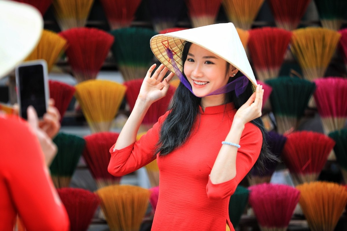 Die Kombination aus dem Hut, dem traditionellen „Ao dài“-Gewand und den vietnamesischen Kostümen ist perfekt