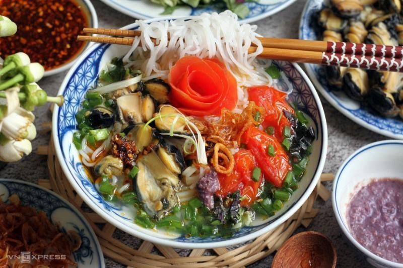 Bún riêu ốc, eine traditionelle vietnamesische Reissuppennudelsuppe mit Schnecken, Tomaten und aromatischen Kräutern.
