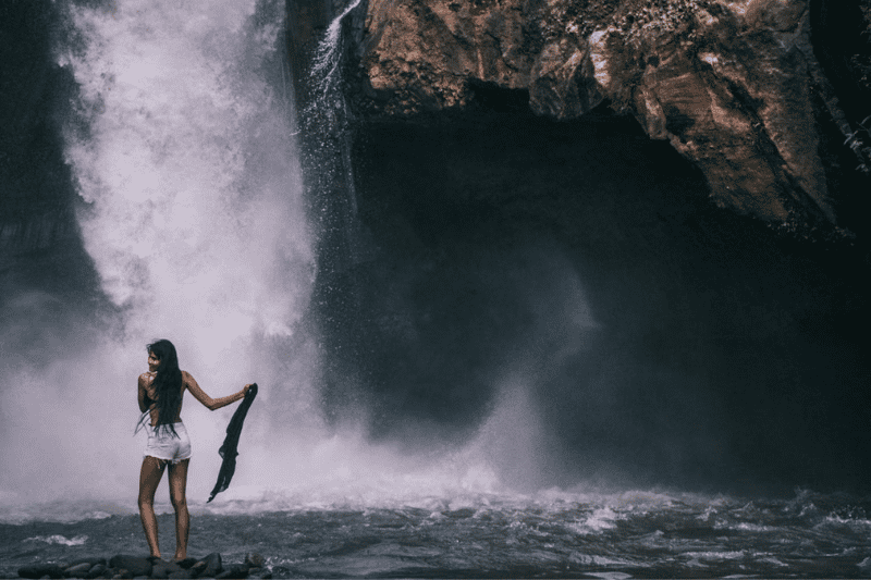 eine frau posiert vor einem majestätischen wasserfall auf bali – eine perfekte kulisse, die ruhe, natur und abenteuer vereint quelle dewa prabawa - pexels